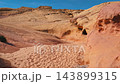 Walking through sandy desert canyon surrounded by colorful red sandstone rock formations, displaying natural erosion and unique geological layers on sunny day in nevada state. Pov hiking hiker 143899315