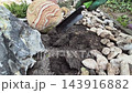 Planting plants in spring. A worker's hand digs a hole for a plant 143916882