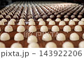 Rows of two-tone chocolate candies move along a conveyor at a confectionery factory. Close-up of automated chocolate production and mass manufacturing of sweets. 143922206
