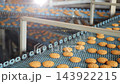 Freshly baked oatmeal cookies move along a conveyor belt at an industrial bakery. Automated cookie production line in a large food manufacturing factory. 143922215