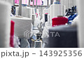 Close up of thread unwinding from large spools inside industrial clothing production facility. Textile yarn feeds continuously into manufacturing equipment. 143925356