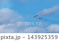 Low angle perspective reveals colored military interceptors banking hard during dynamic aerobatic stunt. Squadron members coordinate precise turns under bright daylight conditions. 143925359