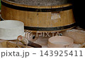 Closeup of traditional medieval rotary stone hand mill with granite millstones grinding wheat grain into fresh coarse wholemeal flour falling from wooden spout into round sieve... 143925411