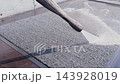 Worker sprays water onto textured surface, creating a wet appearance 143928019