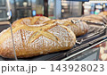 Freshly baked bread being served with tongs in a bakery display case 143928023