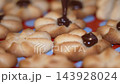 Chocolate drizzle applied to freshly baked cookies on colorful baking mat 143928024
