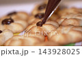 Piping chocolate onto freshly baked cookies in a colorful kitchen setting 143928025