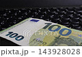 Euro banknote placed on laptop keyboard in close-up view, detailed focus 143928028