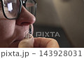 Woman removes nose hair using tweezers in close-up personal grooming session 143928031
