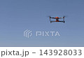 Drone flying in clear blue sky, showcasing aerial technology in motion 143928033