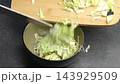 A hand pours a stream of oil into a speckled frying pan 143929509