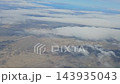 Argentina - October 11, 2026: View from an airplane window of scattered clouds over the vast Patagonian landscape, showing the terrain through breaks in the cloud cover. 143935043