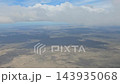 Argentina - October 11, 2026: Expansive view of the Patagonian landscape beneath a cloudy sky from a passenger aircraft, showing distant terrain and atmospheric layers during flight. 143935068