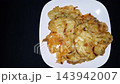 Crispy Golden Bakwan Fritters on Plate with Copy Space, served on a white plate against a dark background. 143942007