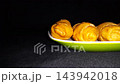 Golden Fried Banana Molen Pastries on Plate with Copy Space. a popular Indonesian fried banana pastry, moving sideways on a vibrant green and white plate against a dark background. 143942018