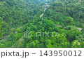 Aerial view of a winding asphalt road cutting through dense tropical rainforest mountains with a 143950012