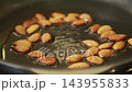 Almonds roasting in hot oil in a frying pan 143955833