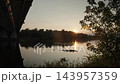 Sunset over a wide river with forest shore and bridge silhouette 143957359