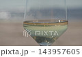 Glass of white wine against a blurred sea and sandy beach 143957605