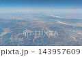 Aerial view of mountains and a lake from an airplane at high altitude 143957609