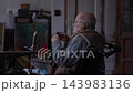 Senior elderly master jeweler in wheelchair works in a workshop 143983136