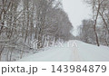 Snowy road in forest, snow falling 143984879