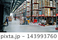 Forklift operators move palletized goods through aisles of a large distribution warehouse. Industrial logistics, cargo handling, inventory storage and supply chain operations. 143993760