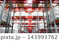 Large industrial warehouse with rows of high storage racks holding white bags on wooden pallets. Logistics, bulk material storage, inventory management and distribution center operations. 143993762