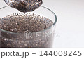 Chia Seeds Swelling in Water Gel Formation Close Up on White Studio Table 144008245