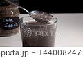 Chia Seeds Gel Formation in Water: Close-Up of Hydrating Seeds on Glass in Studio Kitchen 144008247