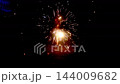 New year ground firework fountain spraying orange sparks in dark night with red flame glow 144009682