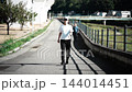 河川敷の遊歩道をウォーキングする女性 144014451