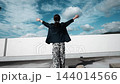 青空に向かって両手を広げる女性の後ろ姿 144014566
