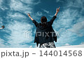 青空に向かって両手を広げる女性の後ろ姿 144014568