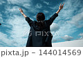 青空に向かって両手を広げる女性の後ろ姿 144014569