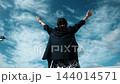 青空に向かって両手を広げる女性の後ろ姿 144014571