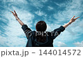 青空に向かって両手を広げる女性の後ろ姿 144014572
