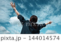 青空に向かって両手を広げる女性の後ろ姿 144014574
