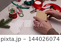 Kraft Gift Box Being Wrapped for Christmas on a Cozy Home Craft Table 144026074