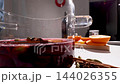 Mulled wine being prepared in a transparent glass pot as spices are added 144026355