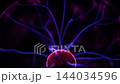Selective focus on the curved glass surface of a plasma ball showing blue electric filaments and purple glowing gas in a dark scientific setting. 144034596